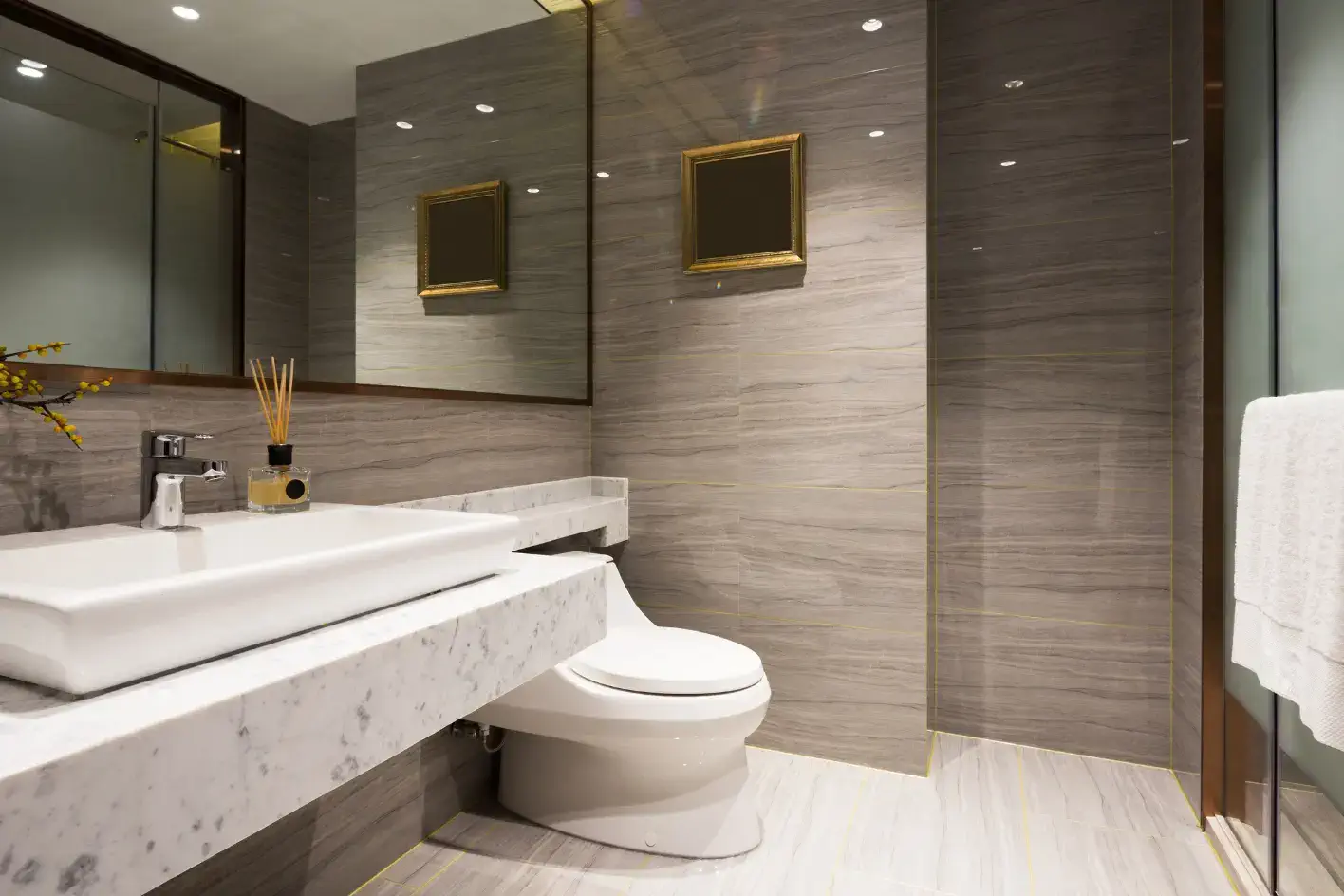 Mermer tezgahlı, gold detaylı gri lüks banyo tasarımı.