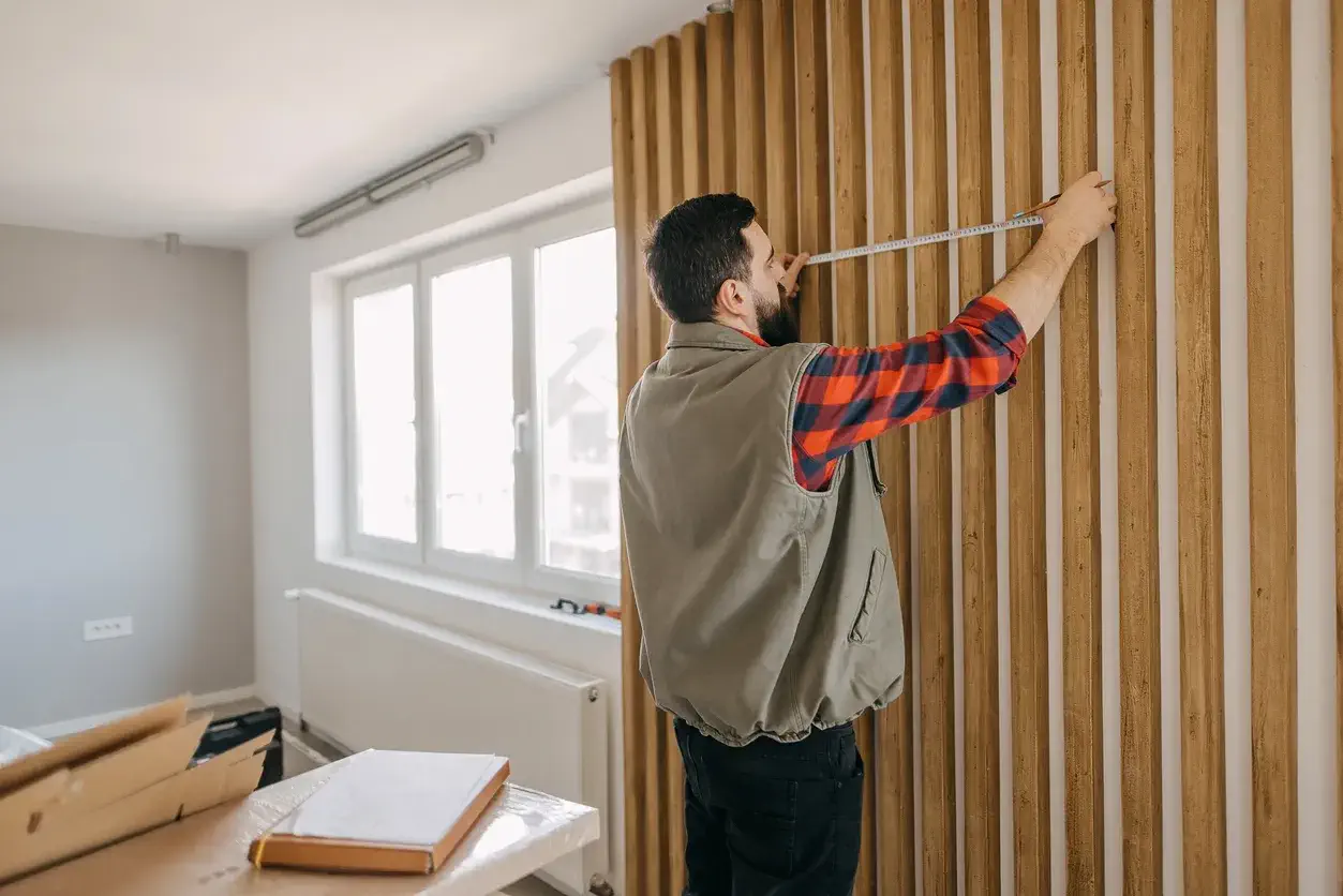 Salon dekorasyonu için ahşap duvar paneli ve dekoratif çıta uygulaması ölçüsü alan usta.